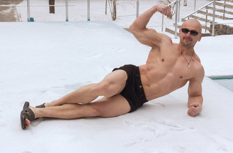 在雪地上躺在户外的健美运动员的真实肖像