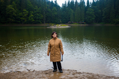 幸福的老年妇女享受美丽的大山湖。 森林湖附近的高级旅游妇女自拍动作相机和谐概念