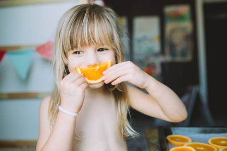 可爱的小女孩在家吃橘子的画像