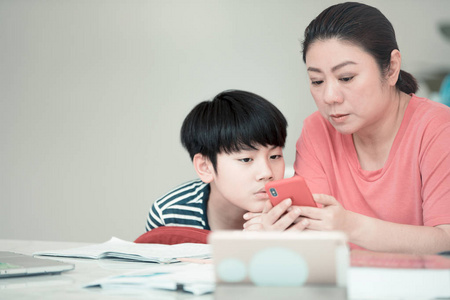 亚洲男孩与母亲教和学习您的家庭作业