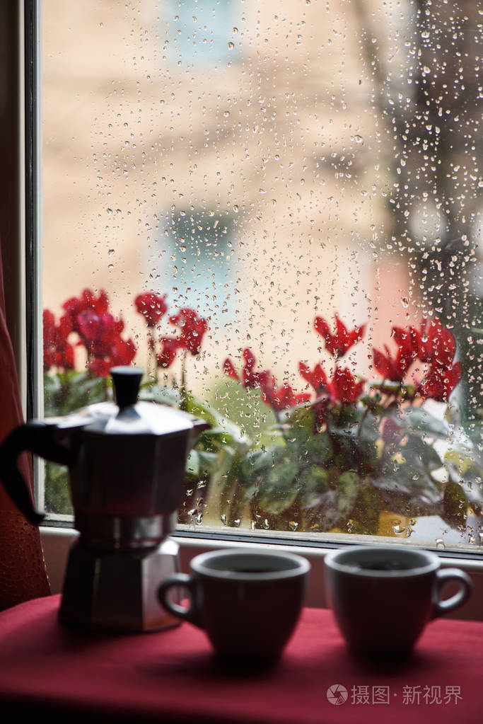 热咖啡杯和咖啡机在窗前雨滴