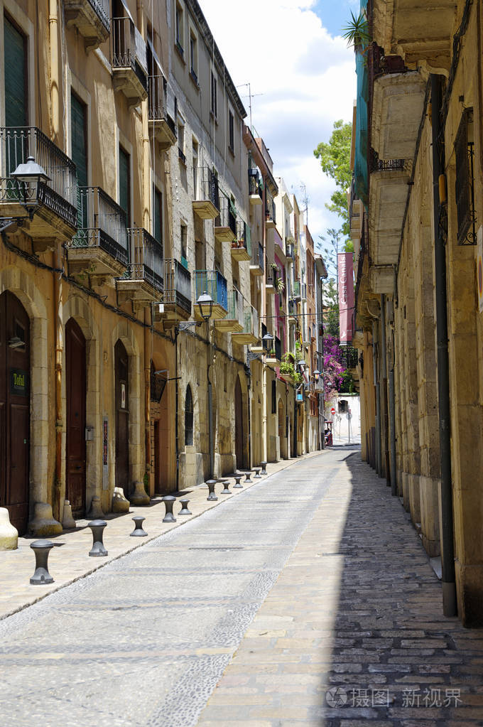 在晴朗的晴天, 旧欧洲城镇冷清的街道.加泰罗尼亚旧城区的明亮城墙