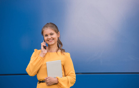 微笑年轻的女实业家在电话拿着平板电脑