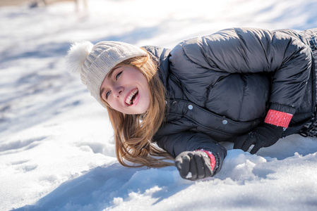 年轻可爱的女人躺在玩和享受冬天的雪