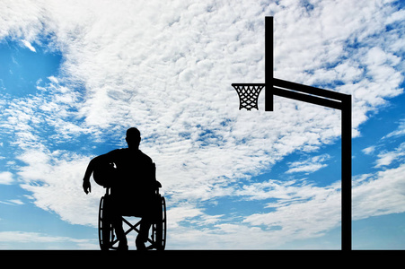 残疾人篮球运动员的剪影在他的手拿着球在轮椅上
