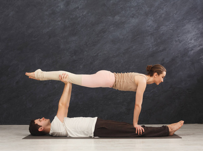 年轻夫妇在垫子上练习 acroyoga