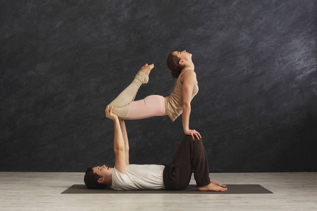 年轻夫妇在垫子上练习 acroyoga