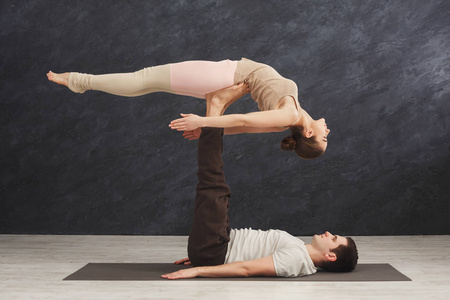 年轻夫妇在垫子上练习 acroyoga