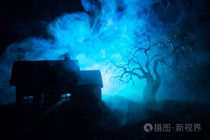 老房子与幽灵在晚上与幽灵树或遗弃闹鬼的恐怖屋在色调模糊的天空与光