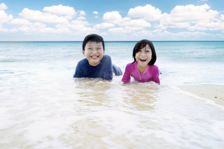 两个欢快的孩子在海滩上玩浪