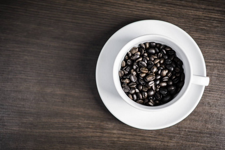 咖啡豆在白色杯子上的木材背景。