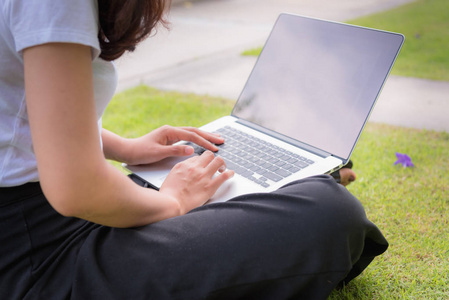 年轻女子享受她的笔记本电脑在花园草