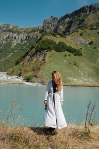 在山的背景下, 一个女孩站在湖边