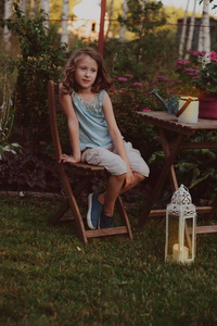 梦幻浪漫的女孩子在晚上的夏日花园放松，装饰着灯笼和烛台灯。