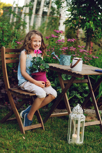 快乐的女孩在夏天的花园里玩，把天竺葵花放在锅里。 教孩子们热爱自然，爱护植物