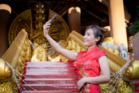 肖像美丽的年轻女孩。 中国妇女在中国新年期间穿着传统服装，在文化季节期间很高兴。 中国传统红色旗袍女性。