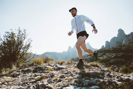 强壮健康的中年人在山公园的生活方式选择上穿着专业的运动服，穿着太阳光耀斑，在超级马拉松或跑步比赛中在岩石和悬崖上奔跑