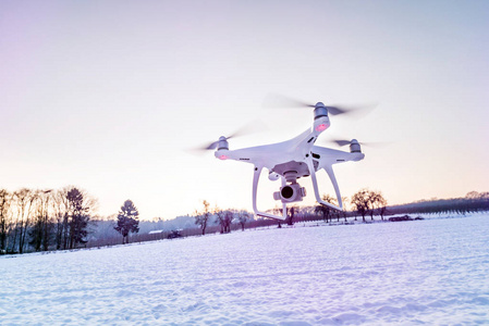 白色无人机相机漂浮在空气中的白雪和田野