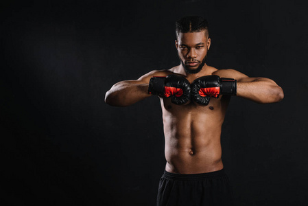 美国黑人拳击手戴着拳击手套看着隔离在黑色上的摄像机