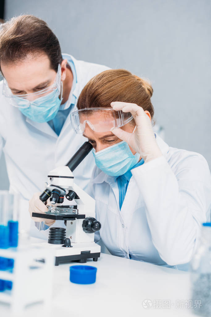 身穿白大褂戴着医用手套戴着护目镜的科学家共同进行实验室科学研究