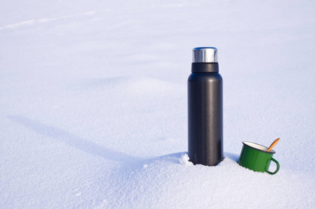 雪中的热水瓶和杯子