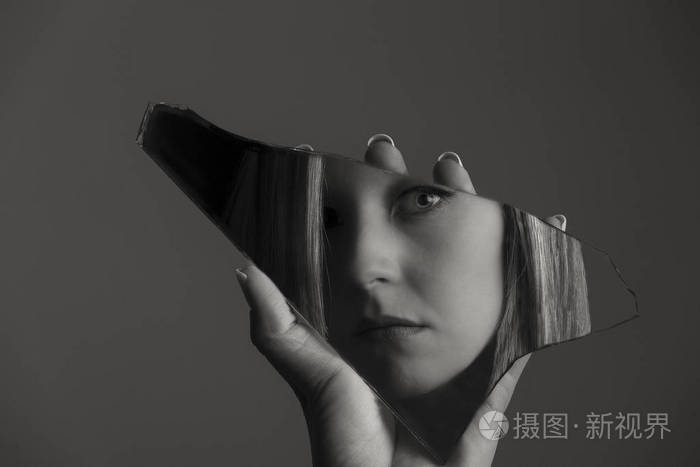 女人看着她的脸在破碎的镜子的碎片艺术 c