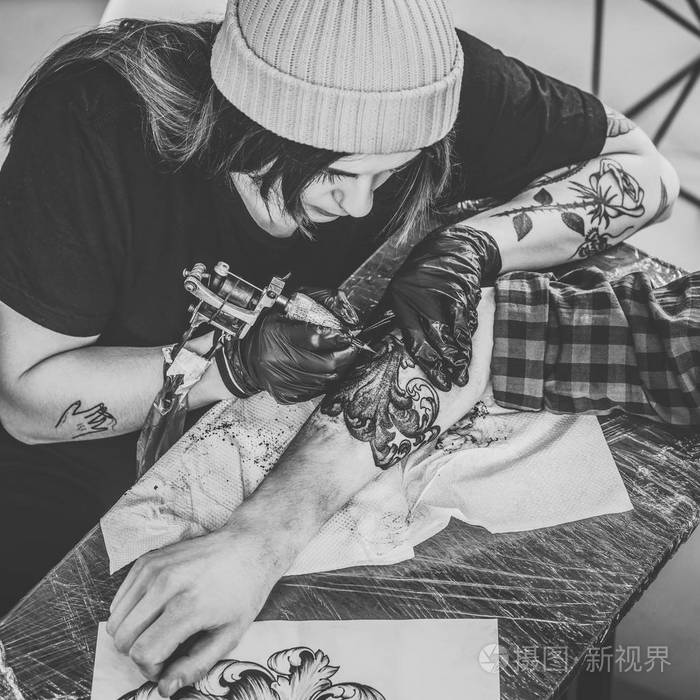 男女纹身师在工作室纹身过程中的黑白照片