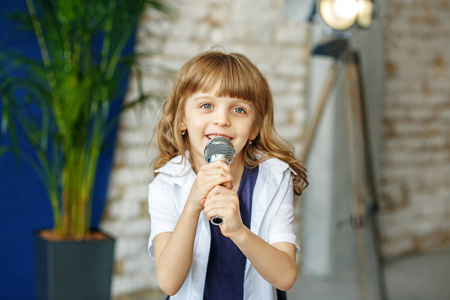 一个漂亮的小女孩用麦克风唱歌。概念是 ch