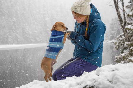 女孩在雪地里和她的狗玩。 在加拿大温哥华以北的斯夸米什和惠斯勒附近拍摄。 概念爱情友谊关怀