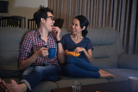 笑的亚洲夫妇吃爆米花，看喜剧电影