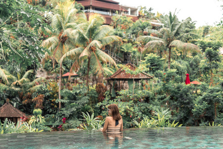 快乐的年轻女子在热带无限游泳池。巴厘岛豪华度假村