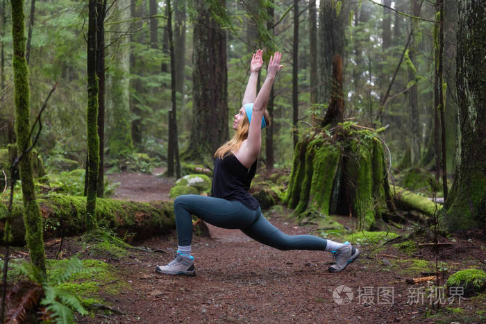 年轻的白种人女孩正在雨林里练习瑜伽。 在加拿大温哥华北部的Capilano峡谷拍摄。