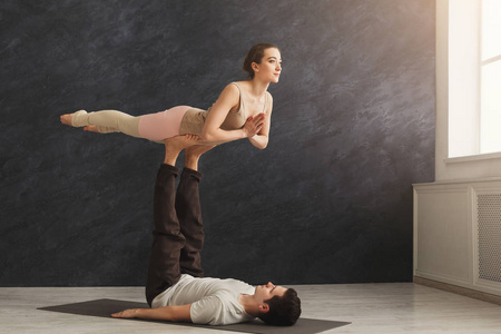 年轻夫妇在垫子上练习 acroyoga