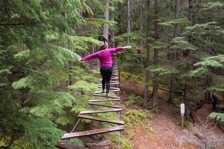 高加索女人在树间高高的电缆上享受着自己。 靠近惠斯勒不列颠哥伦比亚省加拿大。