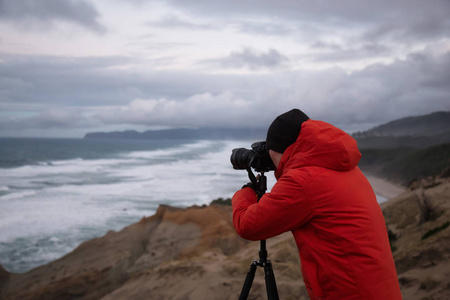 摄影师正在拍摄俄勒冈州海岸美丽的海滨景色。 拍摄于基万达角太平洋城市在多云的冬季日出。