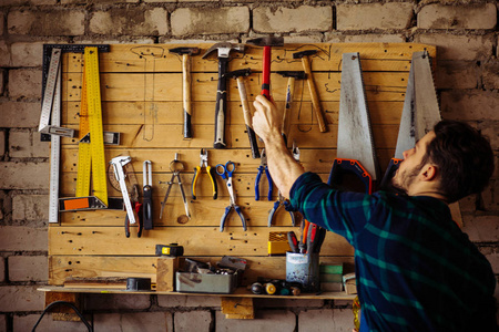 人用工具从墙上拿锤子照片