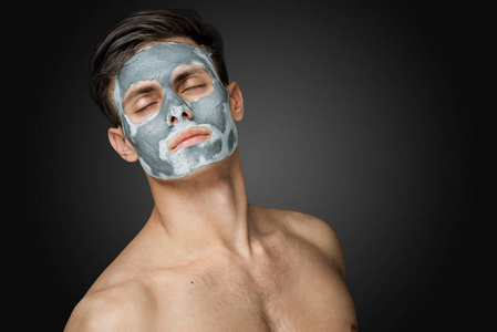 一个美丽的年轻人的肖像与一个面部粘土面罩脸和身体护肤治疗。
