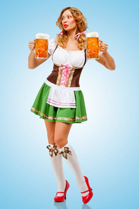 年轻的啤酒节女人穿着传统的巴伐利亚连衣裙，在蓝色背景上供应两个啤酒杯。