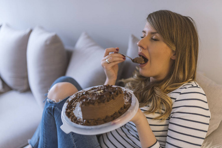美丽的女孩喜欢吃巧克力蛋糕. 漂亮的年轻女人吃甜蛋糕.