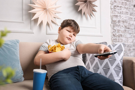 超大电视超重的男孩看电视与零食室内照片