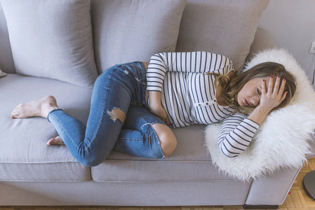 年轻漂亮的女人胃痛。 月经疼痛的女人抱着她疼痛的腹部疼痛的概念。 有腹痛的妇女胃部不适或月经痉挛。 接近年轻女性。 真正的人。 