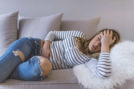 年轻漂亮的女人胃痛。 月经疼痛的女人抱着她疼痛的腹部疼痛的概念。 有腹痛的妇女胃部不适或月经痉挛。 接近年轻女性。 真正的人。 