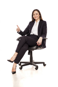微笑的女商人坐在办公椅上，伸出大拇指