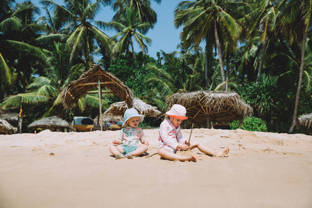 两个可爱的小妹妹在热带海滩玩沙子