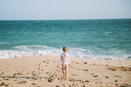 可爱的小女孩在沙滩上散步