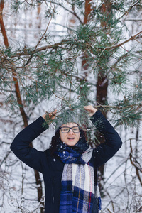 可爱的女孩在玻璃松树树枝下冬季在雪