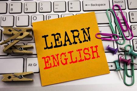 写显示学习英语的文字。语言学校的商业概念在白色键盘背景上写在粘纸条纸上