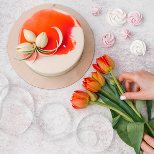 女性手的组成，手持郁金香，白色和红色装饰的蛋糕丝带和月桂