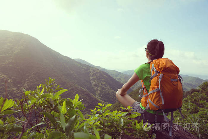 坐在山顶悬崖边上的女子背包客