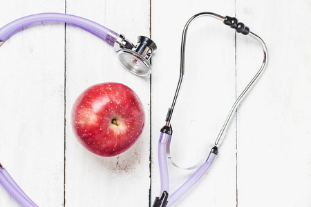 医用听诊器和苹果水果超过木质背景。h